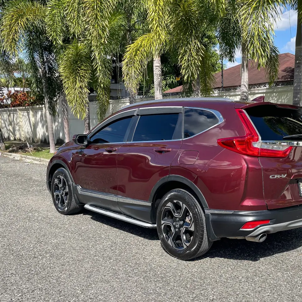 Red Honda CR-V viewed from the side and rear beside palm trees